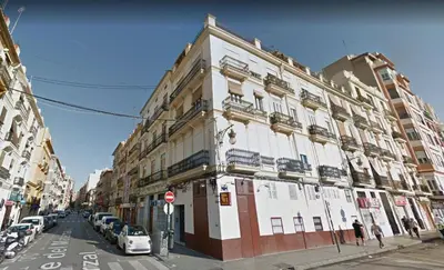 a tall white building on a city street with cars at Main Central Station Apartment in Valencia