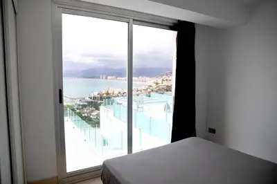 a bedroom with a large window with a view of the ocean at Apartamentos turísticos Cullera in Faro de Cullera