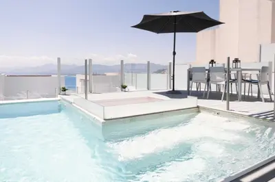 a swimming pool with an umbrella and a table and chairs at Apartamentos turísticos Cullera in Faro de Cullera