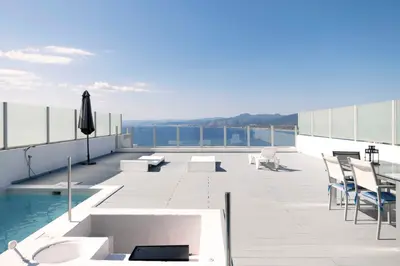 a patio with chairs and a pool on top of a building at Apartamentos turísticos Cullera in Faro de Cullera