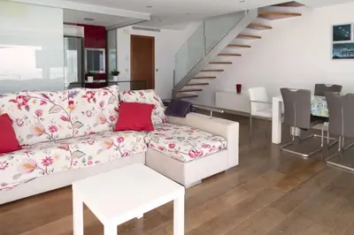 a living room with a white couch and a staircase at Apartamentos turísticos Cullera in Faro de Cullera