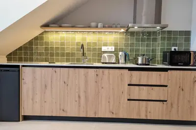 a kitchen with wooden cabinets and green tiles at Renovado Estudio privado en la playa in Valencia
