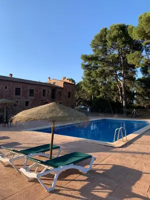 a chair and an umbrella next to a swimming pool at Masia de San Juan - castillo con piscina en plena Sierra Calderona in Segorbe