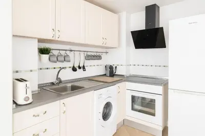 a white kitchen with a sink and a dishwasher at Encantador apartamento junto al Mediterraneo by Hometels in Puerto de Sagunto