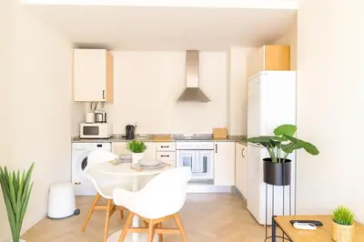 a kitchen with white cabinets and a table and chairs at Encantador apartamento junto al Mediterraneo by Hometels in Puerto de Sagunto