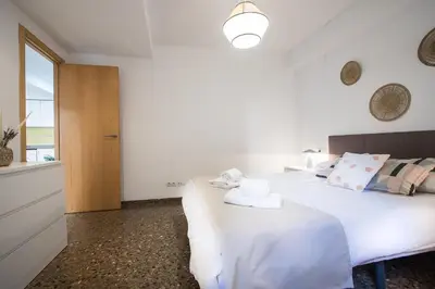 a white bedroom with two beds and a window at Apartamentos Carmen in Valencia
