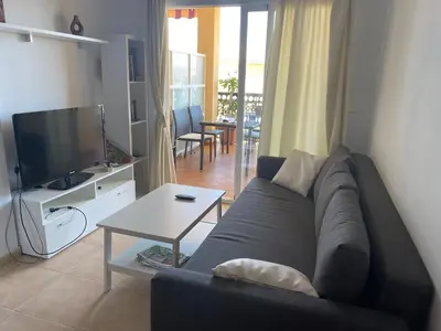a living room with a couch and a television at Urbanización Mar de Canet, 2 dormitorios con piscina comunitaria, garaje y wifi in Canet de Berenguer