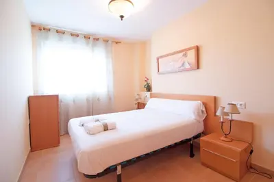 a bedroom with a large white bed with a window at Global Vacacional, Apartamento en Marjal de Corinto con Piscina in Sagunto