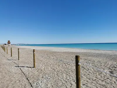 a fence on a beach with the ocean in the background at Global Vacacional, Apartamento en Marjal de Corinto con Piscina in Sagunto