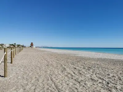 a sandy beach with a fence and the ocean at Global Vacacional, Apartamento en Marjal de Corinto con Piscina in Sagunto