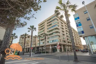 a large building on a city street with palm trees at Front Sun Beach Apartment in Valencia