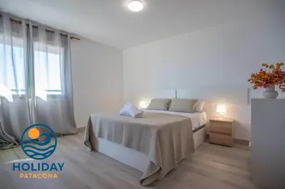 a white bedroom with a bed and a window at Front Sun Beach Apartment in Valencia