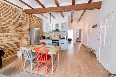 a kitchen with a wooden table and red chairs at Beams & Bricks in Valencia