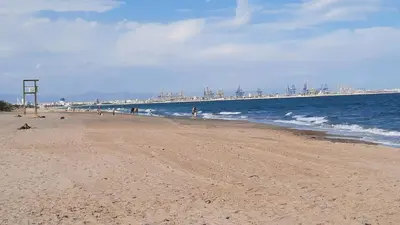 a beach with people on it with a pier in the background at Anna, embrujo de la naturaleza in Anna