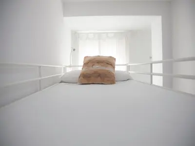 a white bed with a bag sitting on top of it at Flats Friends Tetuan in Valencia