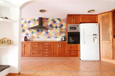 a kitchen with wooden cabinets and a white refrigerator at Global Vacacional, Adosado en la playa con piscina in Sagunto