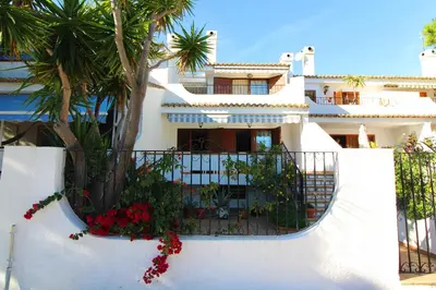 a white house with flowers on a fence at Global Vacacional, Adosado en la playa con piscina in Sagunto
