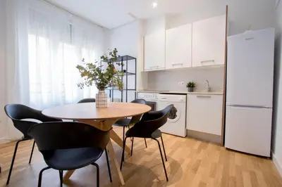 a kitchen with a table and chairs and a refrigerator at Apartamentos San Vicente in Valencia