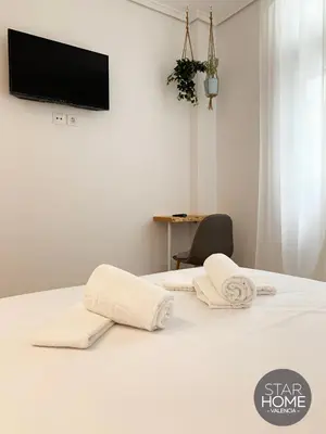 a room with a bed with white sheets and towels at Star Home in Valencia