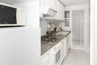 a kitchen with white cabinets and a sink and a microwave at Florazar 3, 8º-B in Cullera