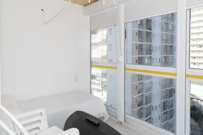a white room with a bed and a large window at Florazar 3, 8º-B in Cullera