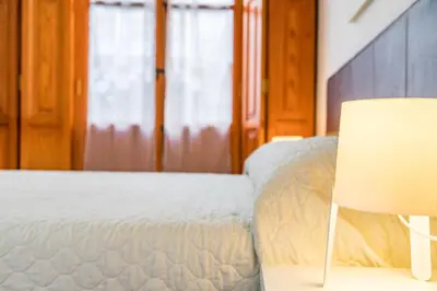 a bedroom with a white bed and a chair at Travel Habitat Plaza de la Virgen in Valencia