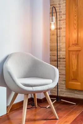 a white chair in a room with a lamp at Travel Habitat Plaza de la Virgen in Valencia