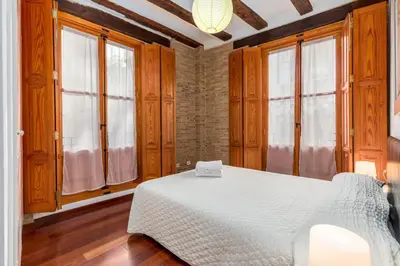 a bedroom with a white bed in a room with windows at Travel Habitat Plaza de la Virgen in Valencia