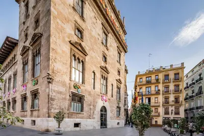 a large stone building in a city with two buildings at Travel Habitat Plaza de la Virgen in Valencia