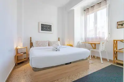 a white bedroom with a bed and a desk at Hostal El Perelló, Valencia in El Perelló