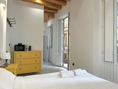 a white bedroom with a bed and a yellow dresser at Mercat Suites in Valencia