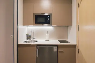 a small kitchen with a sink and a microwave at Palau Suites & Apartments in Valencia