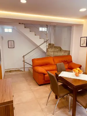 a living room with an orange couch and a table at Casa del Herrero in Chulilla