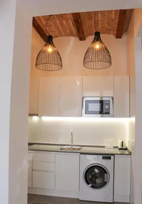a kitchen with a washing machine and two lights at Balaustrada Apartments in Burjasot