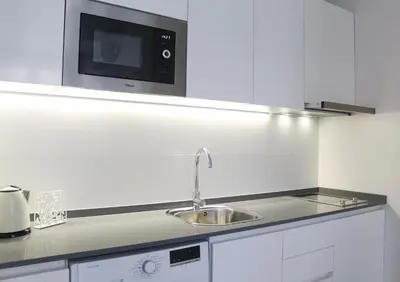 a white kitchen with a sink and a microwave at Balaustrada Apartments in Burjasot