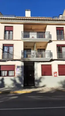 a white building with red doors and balconies on a street at Caudiel entre Sierras in Caudiel