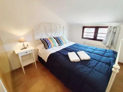 a bedroom with a bed with a blue blanket and a table at Caudiel entre Sierras in Caudiel