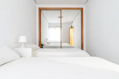 a white bedroom with two beds and a mirror at Bet Apartments - Sunrise Beach Apartments in Valencia