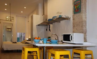 a kitchen with a counter with a microwave and yellow stools at Loft independiente con Piscina compartida en Centro de Valencia in Valencia