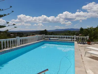 a swimming pool with a white fence and mountains in the background at Casa Loro Loco B&B in Pedralba