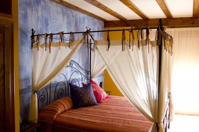 a bedroom with a canopy bed with white curtains at A la Sombra de la Torre in Serra