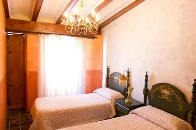 a bedroom with three beds and a chandelier at A la Sombra de la Torre in Serra