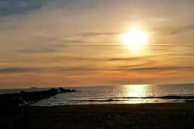 a sunset on a beach with the sun setting over the ocean at Apartamento estudio en playa Puig in Valencia