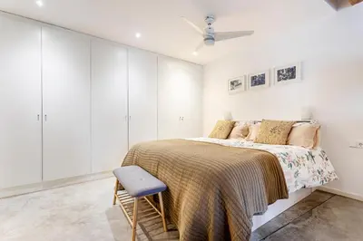 a white bedroom with a bed and a chair at Loft Mercado Mossen Sorell in Valencia