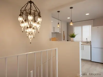 a chandelier in a living room with a kitchen at Increible ático con vistas al Mediterraneo by Hometels in Puerto de Sagunto
