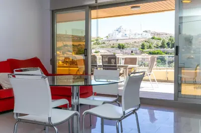 a dining room with a glass table and white chairs at Big Terrace Apartment Cullera in Cullera