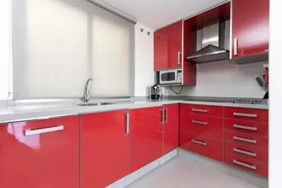 a kitchen with red cabinets and a sink at Big Terrace Apartment Cullera in Cullera