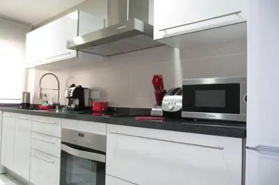 a kitchen with white cabinets and a microwave at piso con estilo cerca de la playa in Cullera