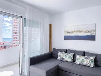 a living room with a gray couch and a window at NUEVO, a 70 metros de la playa y con vistas al mar in Cullera