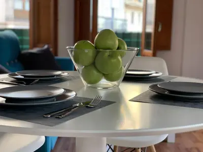 a bowl of green apples on a table with plates at 123rooms in Valencia